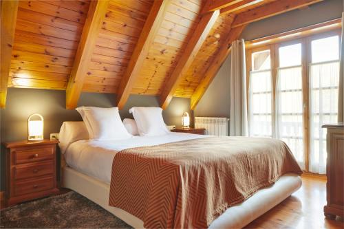 1 dormitorio con cama grande y techo de madera en El Jardí Secret by FeelFree Rentals en Escuñau