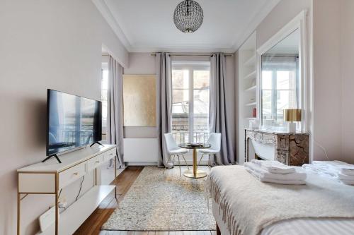 ein weißes Schlafzimmer mit einem Bett, einem TV und einem Schreibtisch in der Unterkunft Charming Studio - 2P Villiers in Paris