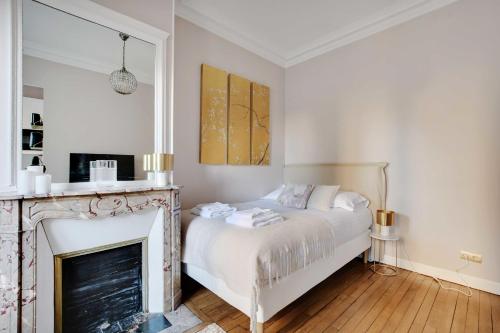 - une chambre avec un lit blanc et une cheminée dans l'établissement Charming Studio - 2P- Parc Monceau, à Paris