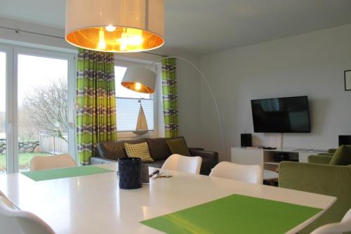 a living room with a table and chairs and a television at Haus-Anker in Wittdün
