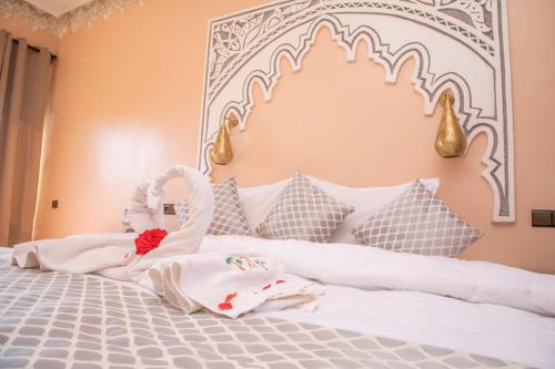 a bedroom with a white bed with a large headboard at Taloute Ecolodge in Skoura