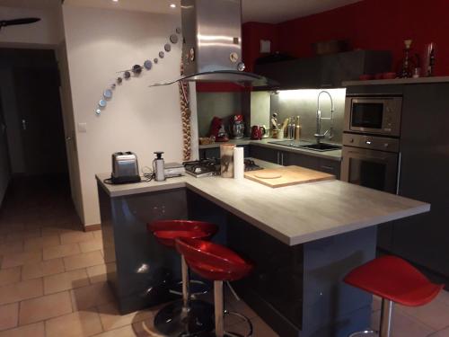 une cuisine avec un comptoir et deux tabourets de bar rouge dans l'établissement Gambetta, à Pont-Saint-Esprit