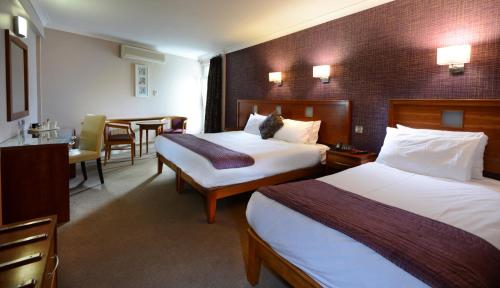 Imperial Hotel Galway في غالواي: غرفة فندقية بسريرين وطاولة