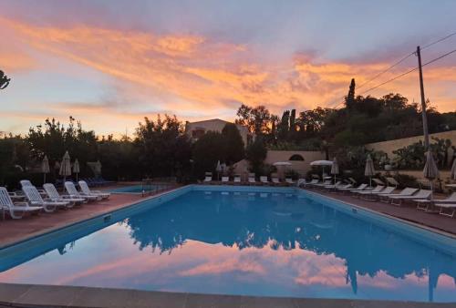 a swimming pool with chairs and a sunset at Hotel Grotticelle in Capo Vaticano