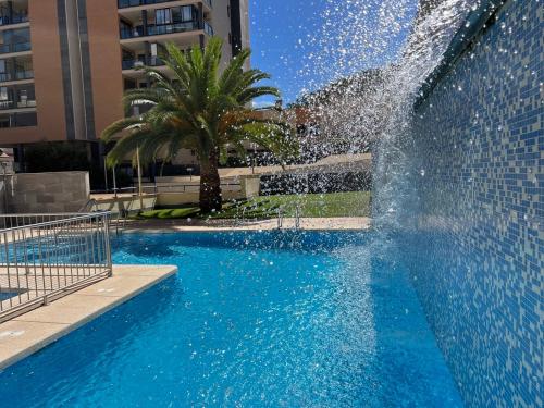 a fountain in a swimming pool in a city at Aura Apartment Benidorm in Benidorm
