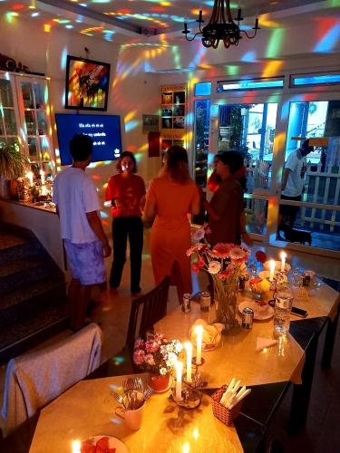 a group of people standing in a restaurant with tables at Pretty Backpackers House in Da Lat