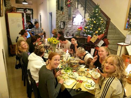 een groep mensen die aan een tafel eten bij Pretty Backpackers House in Da Lat