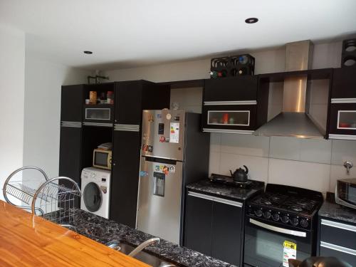 una cocina con electrodomésticos de acero inoxidable y armarios negros en Champa Duplex Premium en San Rafael