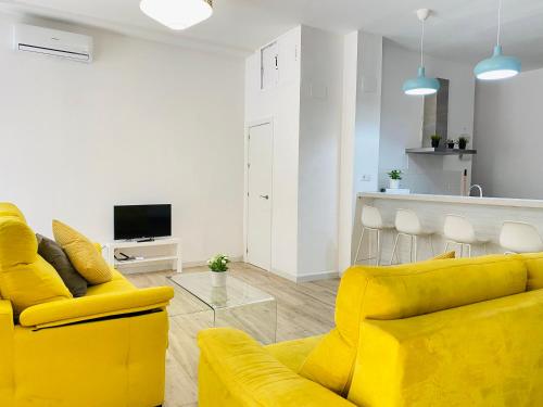 セビリアにあるFlamenca Triana - Apartamento Totalmente Equipado Wifi 2D sofas camas 2 bañosのリビングルーム(黄色のソファ付)、キッチンが備わります。