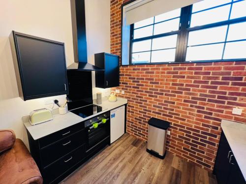 a living room with a tv and a brick wall at Apartment 7 Sullivan House in Hereford