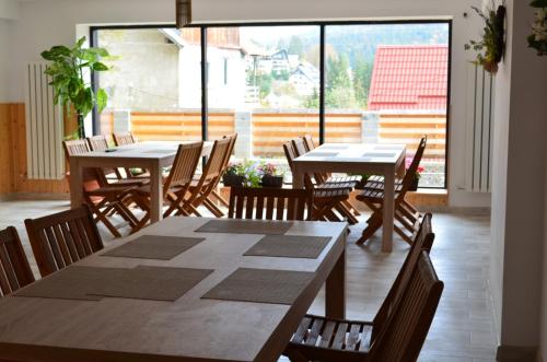a dining room with tables and chairs and a large window at Drag De Munte in Predeal