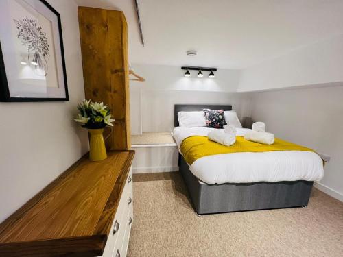 a bedroom with a large bed with a yellow blanket at Apartment 8 Sullivan House in Hereford