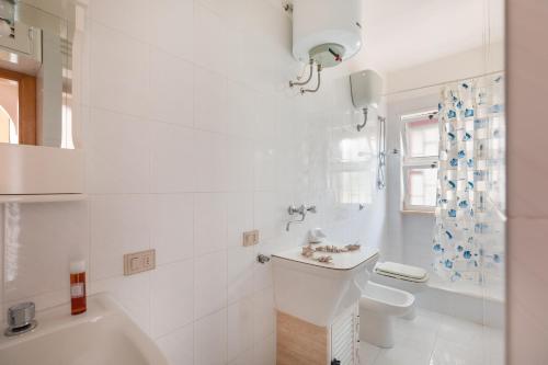 un bagno bianco con vasca e lavandino di Appartamento Orchidea A1 - MyHo Casa a Torre Canne