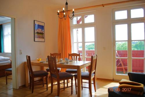 ein Esszimmer mit einem Tisch, Stühlen und Fenstern in der Unterkunft Vineta App. 03 in Heringsdorf