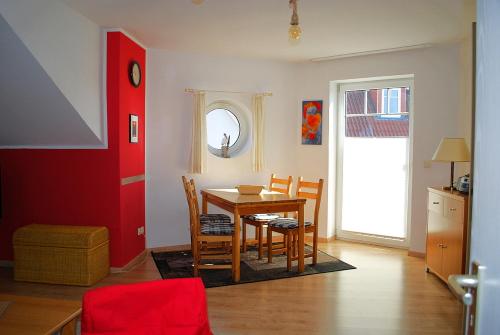 a dining room with a table and chairs and a red door at Wilhelmstr-10-Whg-25 in Ahlbeck