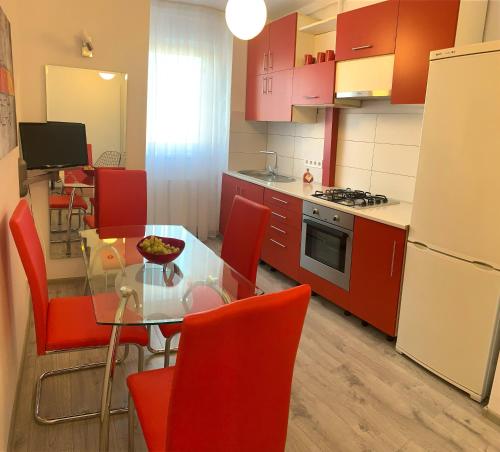 アルバ・ユリアにあるTransylvania Residenceのキッチン(ガラステーブル、赤い椅子付)