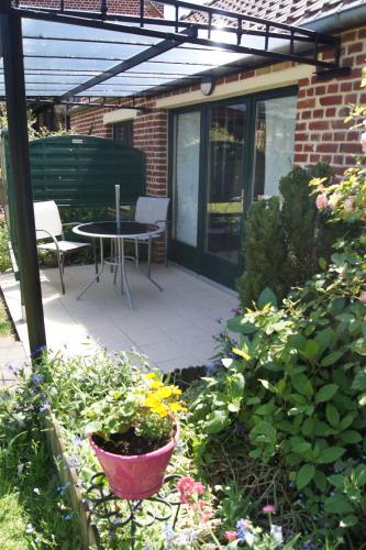 a patio with a table and chairs and flowers at Le Paddock Du Val De Lys in Blessy