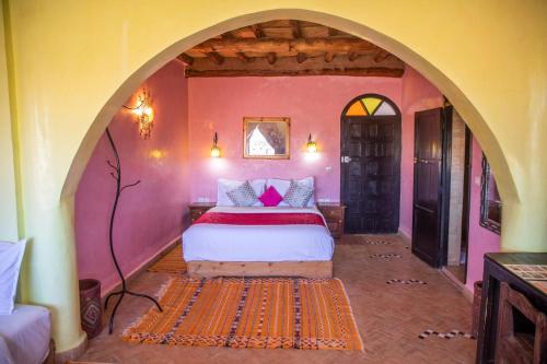a bedroom with a bed in a room with an archway at Taloute Ecolodge in Skoura