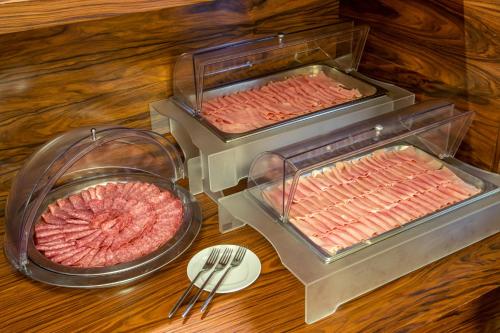 two trays of meat on a table with a plate at Hotel Capannelle Roma in Rome
