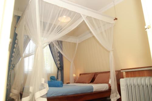 a bedroom with a bed with curtains and a window at L' Oasis de Verdure in Antananarivo