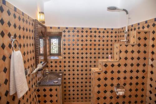 a bathroom with a tiled wall with a sink at Taloute Ecolodge in Skoura