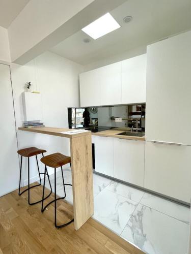 une cuisine avec des armoires blanches et un comptoir avec des tabourets dans l'établissement Superb top floor studio, Biarritz center., à Biarritz
