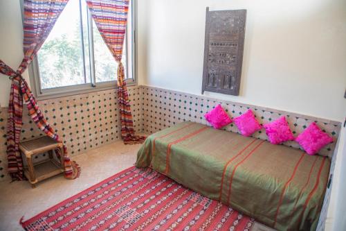 a bedroom with a bed with pink pillows at Taloute Ecolodge in Skoura