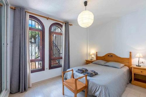 een slaapkamer met een bed, een stoel en ramen bij 797 HR - Pueblo Evita- Andalusian apartment with terrace. in Benalmádena