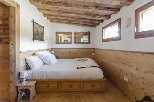 a bedroom with a bed with wooden walls and windows at Charming Studio in Chiave