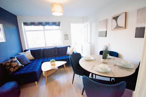 ein Wohnzimmer mit einem blauen Sofa und einem Tisch in der Unterkunft Ideal Lodgings in Whitefield Radcliffe in Manchester
