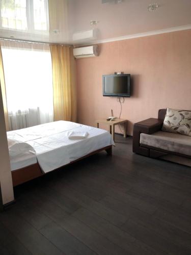 a bedroom with a bed and a couch and a television at Квартира ЛЮКС in Balqash