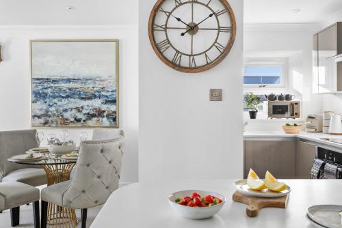 a kitchen and dining room with a large clock on the wall at Seaview Suite at The Corbyn Apartments in Torquay