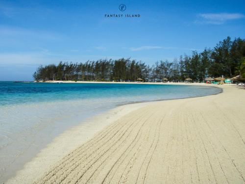a sandy beach with blue water and trees in the background at Fantasy Island Beach Resort and Marina - All Inclusive in First Bight