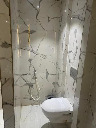 La salle de bains est pourvue de toilettes blanches et d'un mur en marbre. dans l'établissement NT Hotels and Resorts Akridha, à Pondichéry