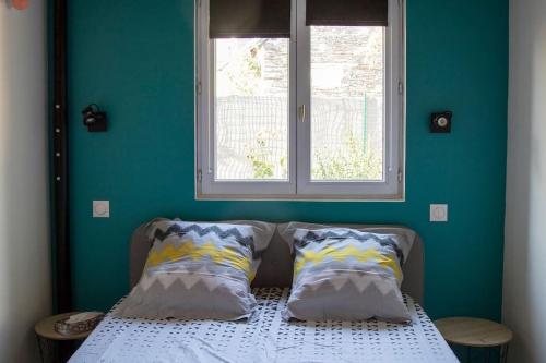 1 dormitorio con 1 cama con 2 almohadas y ventana en La maisonnette de Joséphine en Saint-Jean-des-Mauvrets
