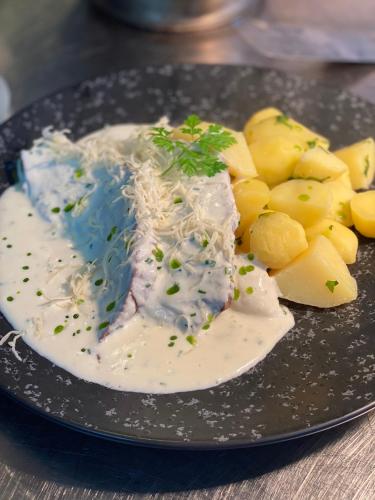 a plate of food with meat and cheese and potatoes at Hotel & Restaurant Zum Riesen in Walldürn