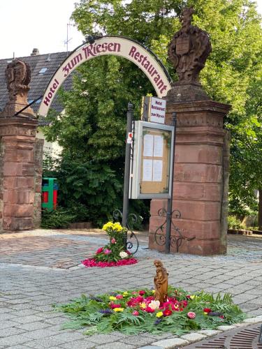 an entrance to a park with a sign and flowers at Hotel & Restaurant Zum Riesen in Walldürn