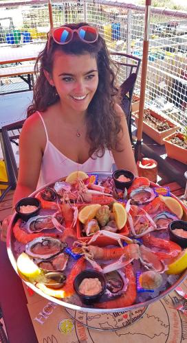 une femme assise devant une grande assiette de fruits de mer dans l'établissement L' Ecume de Mer, à Châtelaillon-Plage