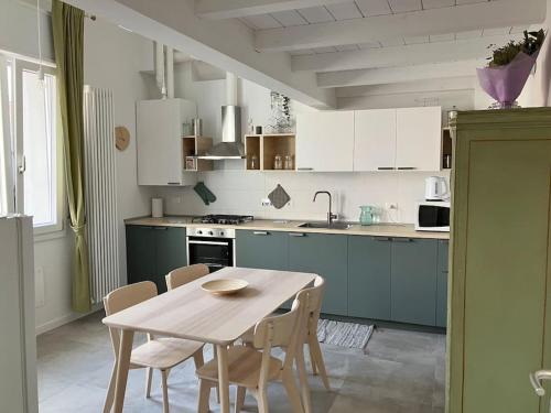 uma cozinha com mesa e cadeiras e uma cozinha com armários brancos em Deliziosa Casetta a Bologna em Bolonha