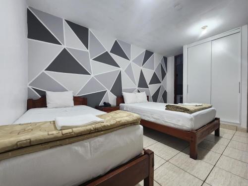 1 dormitorio con 2 camas y pared geométrica en Hotel Villa del Sol en Piura