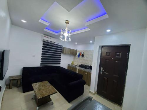 a living room with a black couch and a chandelier at DINERO DIAMOND - ONE BED APARTMENT in Lagos