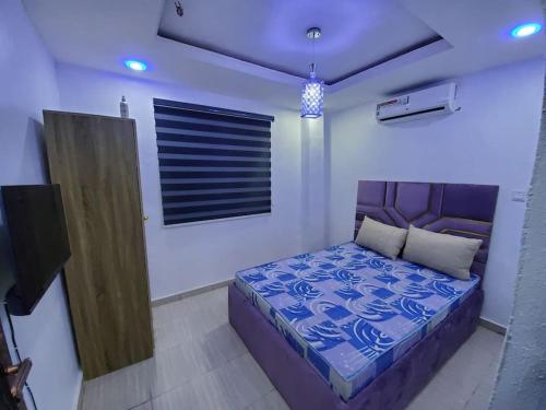 a bedroom with a bed with a blue comforter at DINERO DIAMOND - ONE BED APARTMENT in Lagos