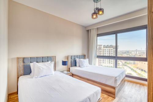 two beds in a room with a large window at LOFTS by Elegant Hospitality in Cairo