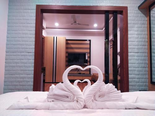 two white swans making a heart on a bed at CHARULATA RESIDENCY in Bolpur