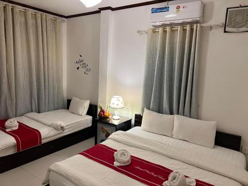 ein Hotelzimmer mit 2 Betten und Vorhängen in der Unterkunft Jasmine Place House in Luang Prabang