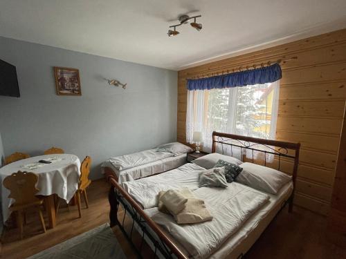 a bedroom with two beds and a table and a window at Pokoje Gościnne U Babci in Zakopane