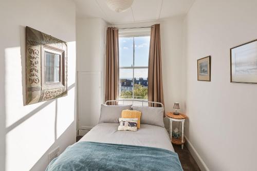 a small bedroom with a bed with a window at Beautiful Sea View Apartment in St Leonards on Sea in St. Leonards