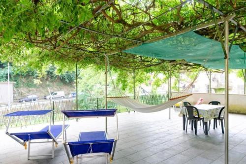 a patio with a hammock and a table and chairs at Il Glicine di Villa Vittoria nel verde a pochi minuti di auto dalle spiagge in Borgonovo