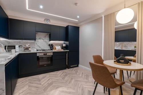a kitchen with blue cabinets and a table and chairs at The Wilton Suite - Your Private 5* Escape! in Glasgow