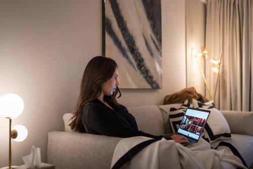 a woman sitting on a couch with a tablet at The Wilton Suite - Your Private 5* Escape! in Glasgow
